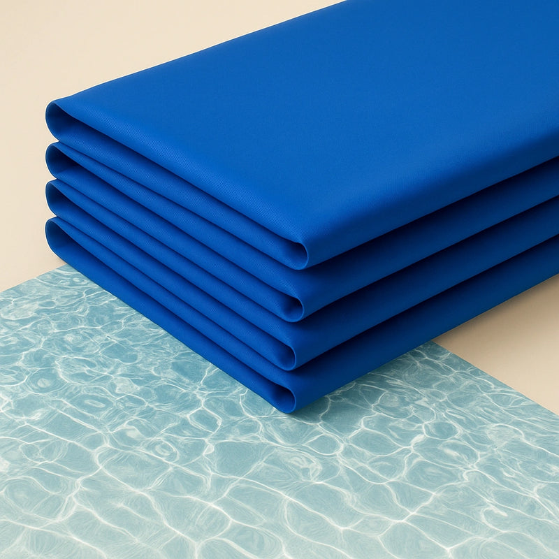 Tappetini refrigeranti blu piegati su fondo chiaro con riflessi d’acqua, ideali per l’estate e facili da riporre